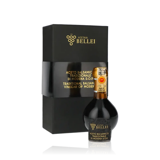Aceto Balsamico Bellei Flasche und Verpackung vor schwarzem Hintergrund.