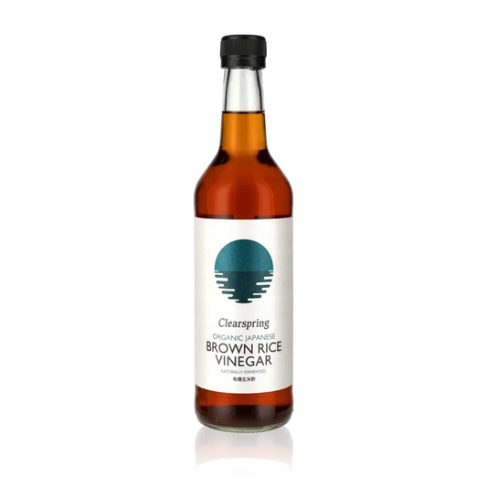 Clearspring brauner Reisessig Flasche vor schwarzem Hintergrund.