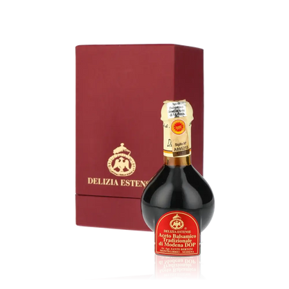 Delizia Estense Balsamico-Essigflasche vor roter Verpackung.