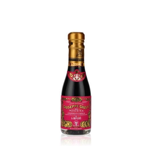 Giuseppe Giusti Himbeer-Balsamessig Flasche vor schwarzem Hintergrund.