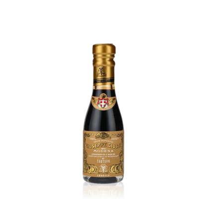 Giuseppe Giusti Trüffel Balsamessig Flasche vor schwarzem Hintergrund.