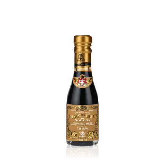 Giuseppe Giusti Trüffel Balsamessig Flasche vor schwarzem Hintergrund.