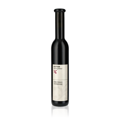 Flasche Acetum Manufaktur Himbeeressig vor schwarzem Hintergrund.