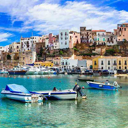 Buntes mediterranes Hafenstädtchen mit kleinen Fischbooten im blauen Meer.