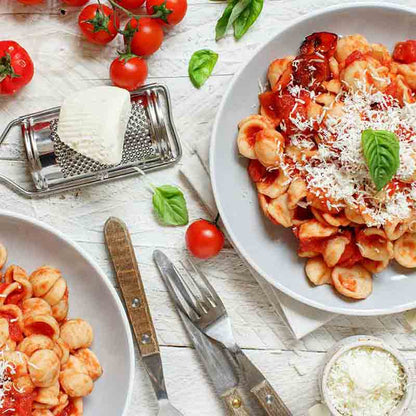 Pasta mit Tomatensauce, Käse, Basilikum und Tomaten auf Tellern.