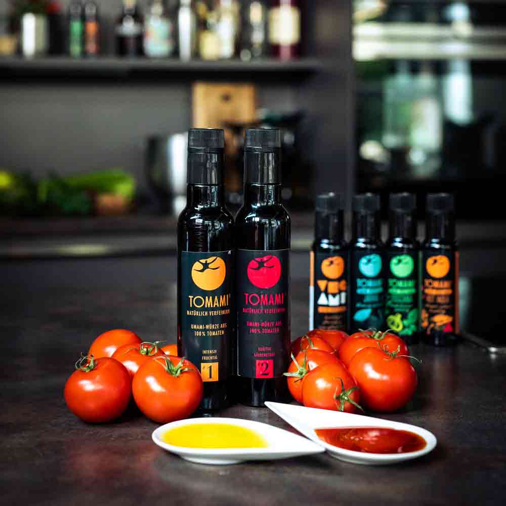 Tomami-Produkte, Tomaten, Olivenöl, Essig, Feinkostflaschen auf Tisch.