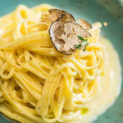 Pasta mit Trüffelcreme auf grünem Teller, Nahaufnahme.