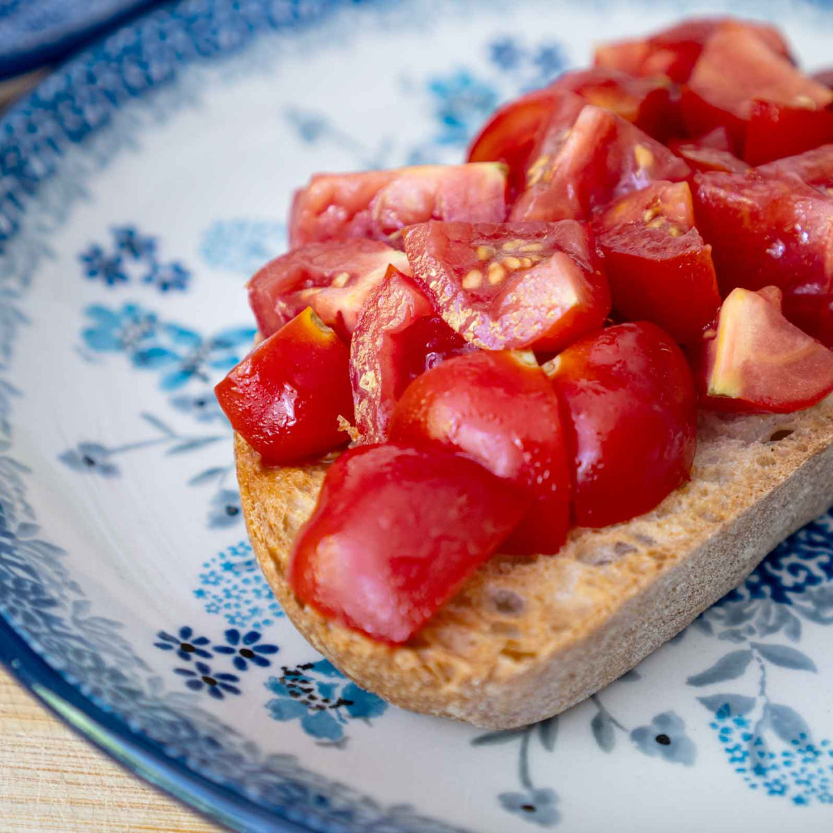 Bruschetta mit Tomaten, Olivenöl, Salz und Weißbrot auf blauem Teller.