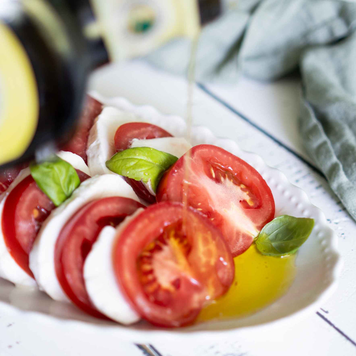 Olivenöl fließt auf einen klassischen Caprese Salat