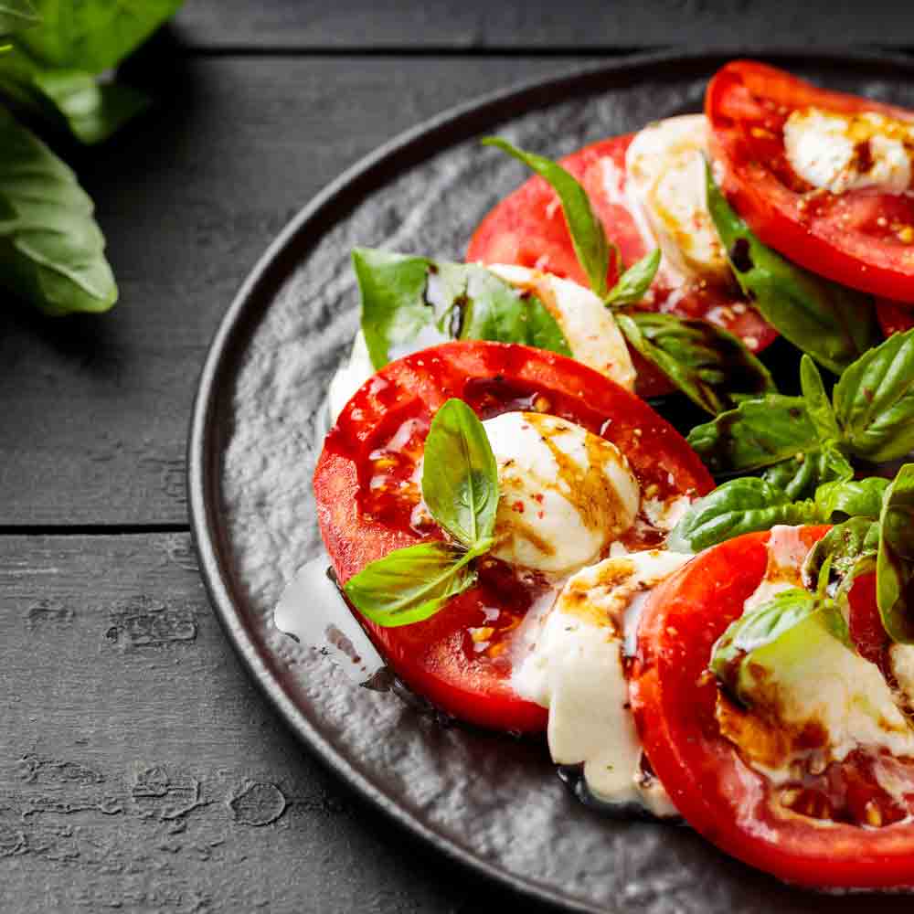 Caprese-Salat mit Tomaten, Mozzarella, Basilikum und Balsamico-Essig.