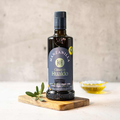 Flasche Casas de Hualdo Manzanilla Olivenöl auf Holzbrett.