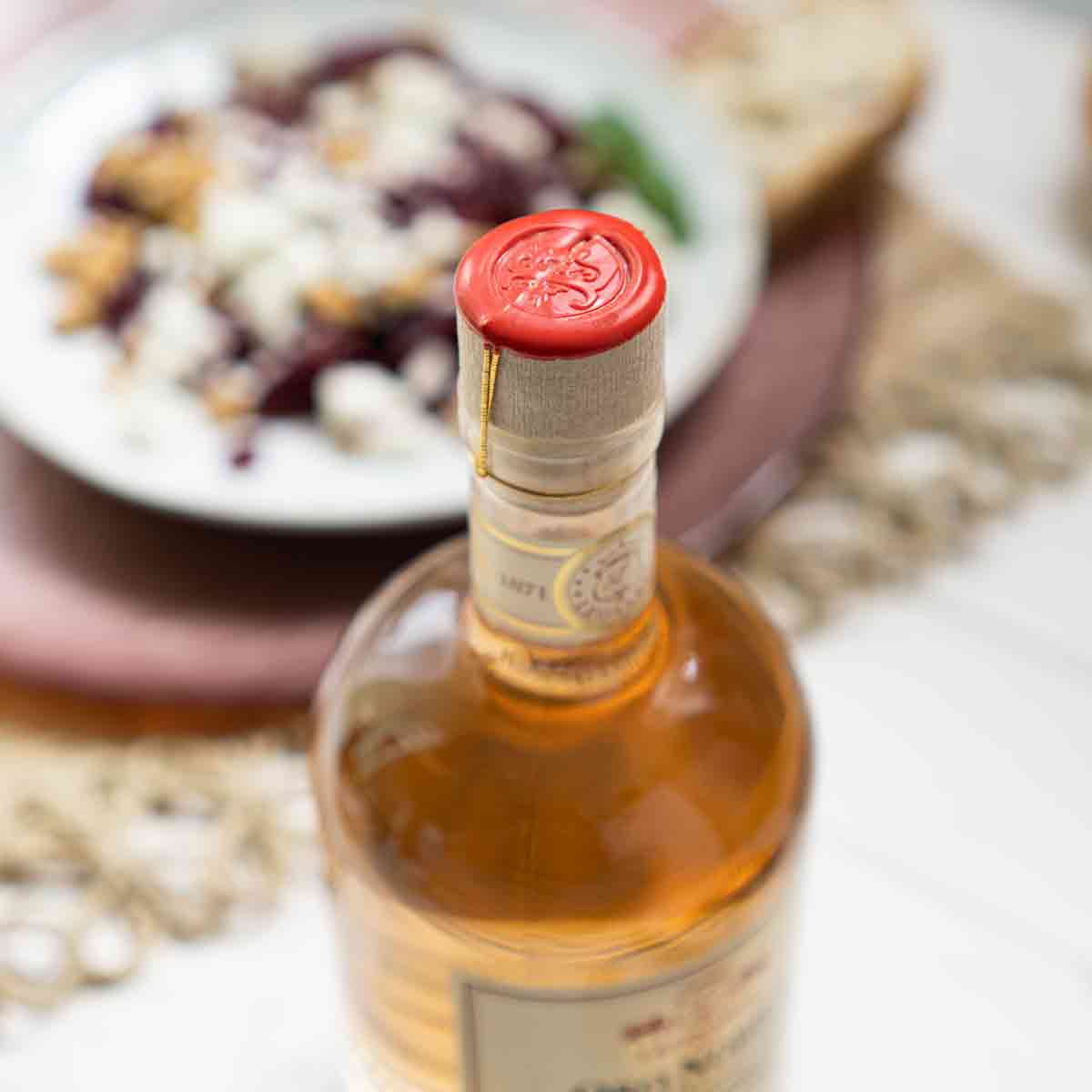 Flasche Leonardi Essig mit rotem Wachsdeckel, Teller Hintergrund.