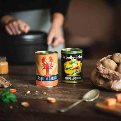 Feinkostprodukte: Hummerbisque, Fischsuppe, Kartoffeln, Brot, Löffel, Hände.