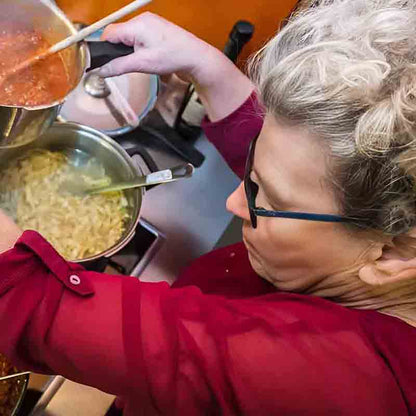 Frau kocht Pasta und Soße.