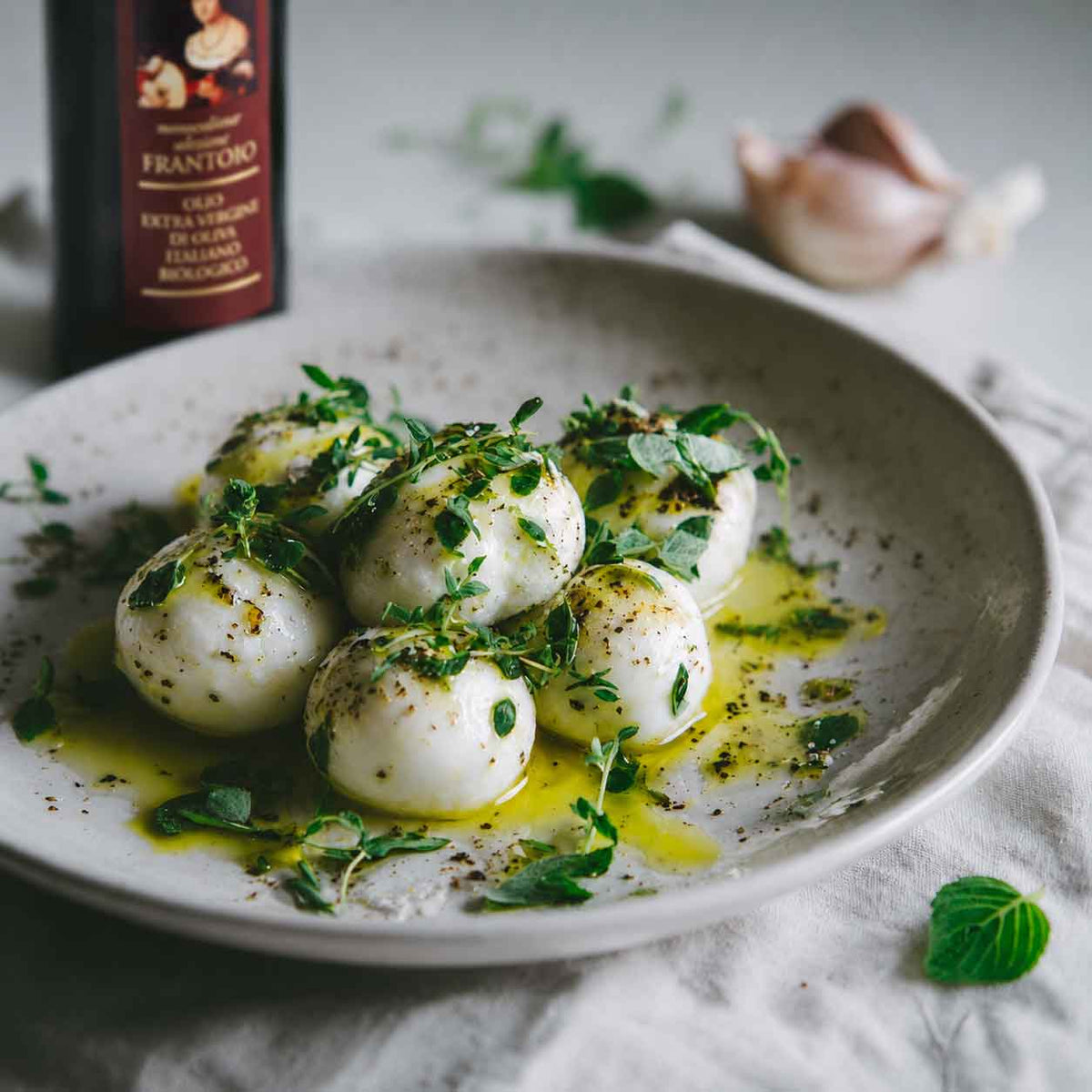 Marinierte Mozzarella auf einem Teller mit Olivenöl und Kräuter Topping