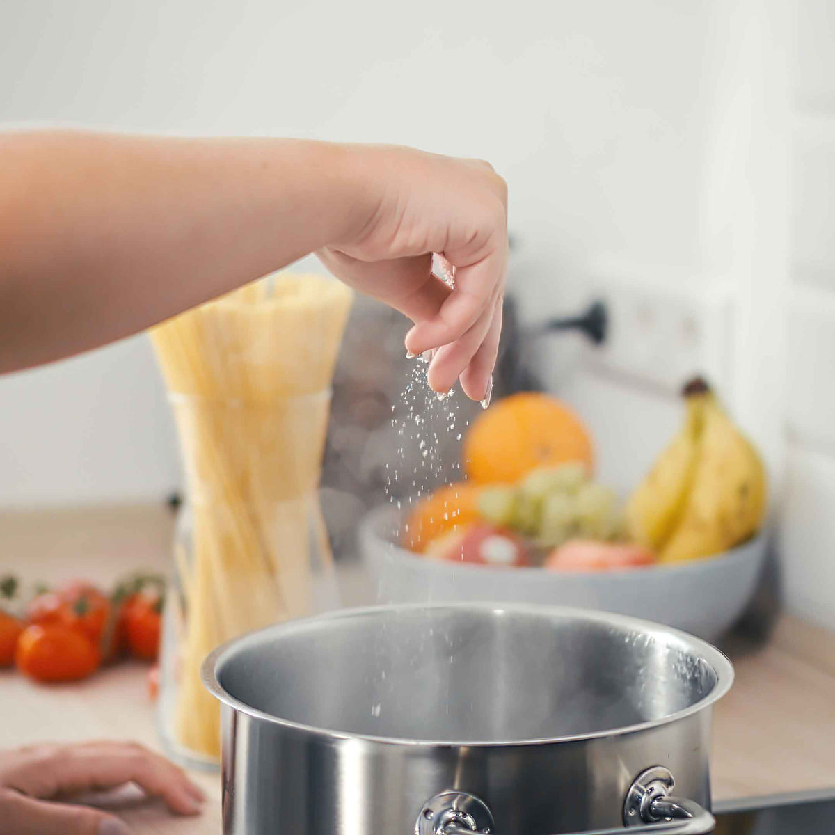 Salz wird in einem Topf mit kochendem Nudelwasser gegeben.