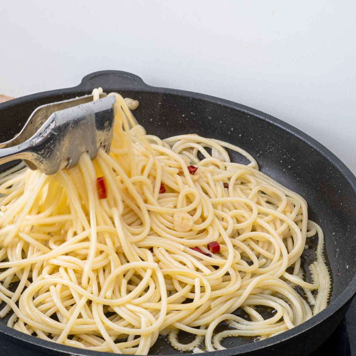 Pasta wird mit Sauce vermengt