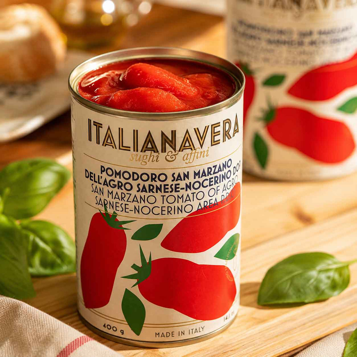 Italienische Tomatendose Italianavera auf Holztisch mit Basilikum.