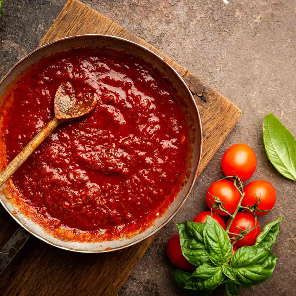 Tomatensugo in Pfanne mit frischen Tomaten und Basilikum.