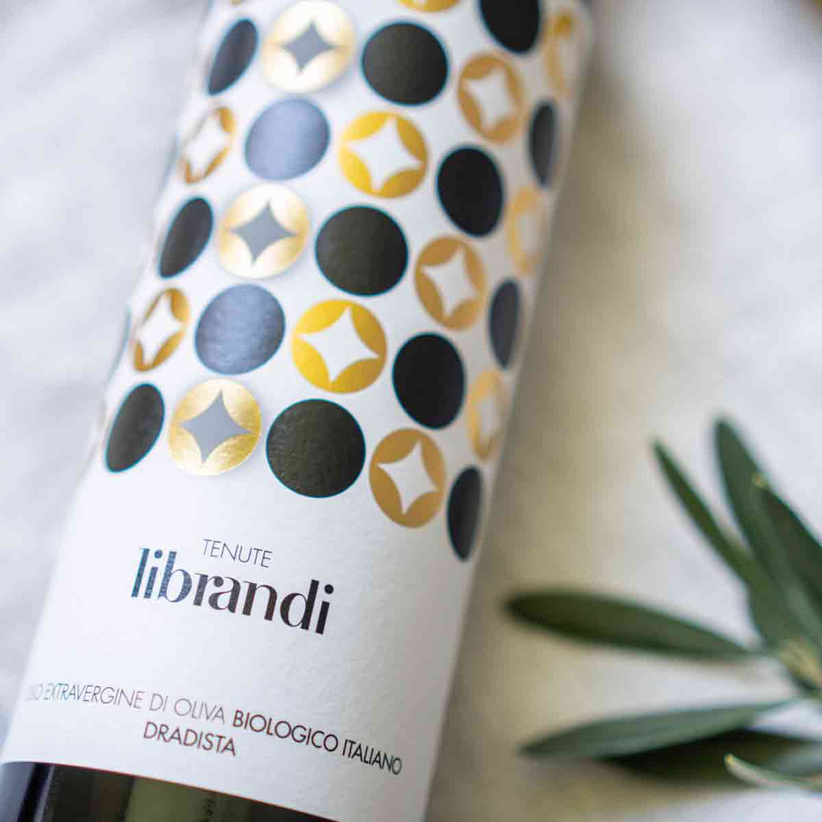 Flasche Tenute Librandi Olivenöl mit Olivenzweig daneben.