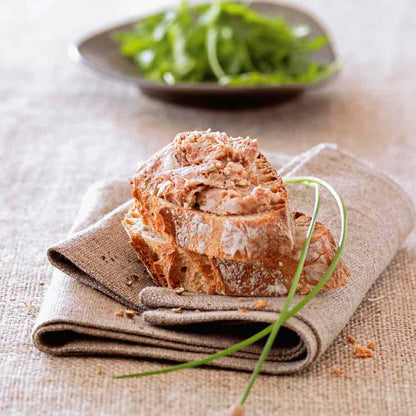 Brot mit Aufstrich auf Leinentuch, Salat im Hintergrund.