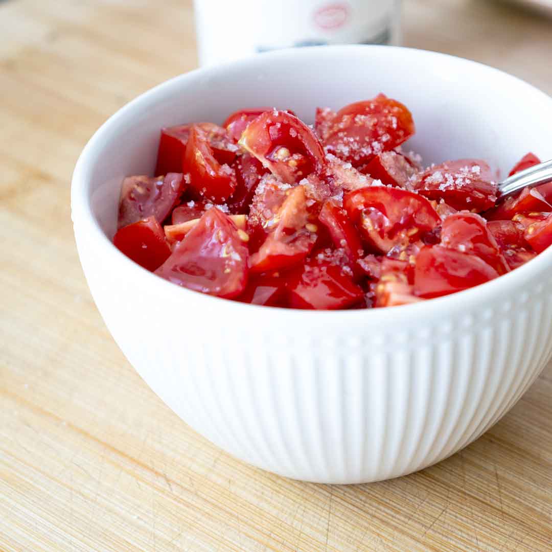 Gewürzte und geschnittene Tomaten in weißer Schüssel
