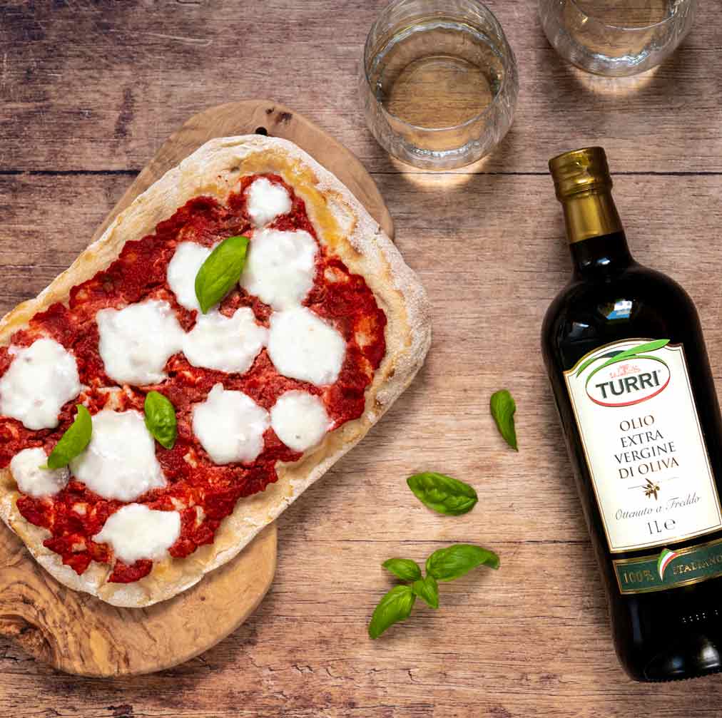 Pizza mit Mozzarella, Turri Olivenöl, Basilikum, zwei Gläser Wasser.